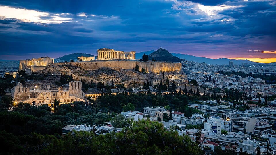 The illuminated Acropolis above Athens beneath blue clouds at daybreak