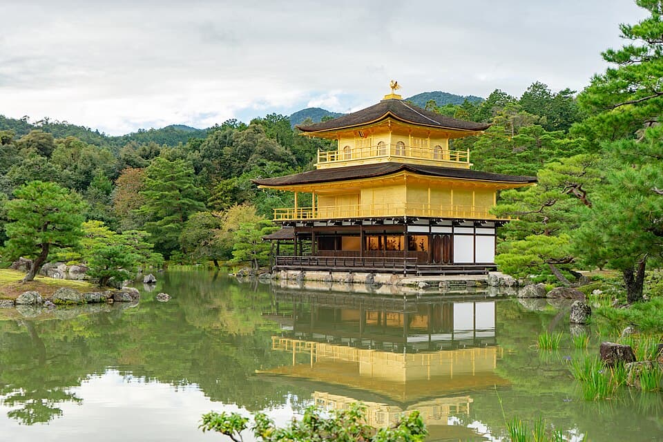 The golden Kinkaku-ji pavilion in Kyoto reflected in a pond among green trees